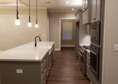kitchen side view of dark gray with white quartz countertop island and pendant lights