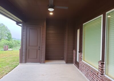 back porch view with dark brown walls and ceiling and large windows set in a light red brick center wall looking from the side of porch