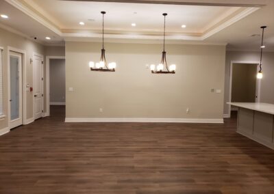 view of dining area with double chandeliers with beige walls and brown wood flooring