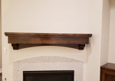 a close up of a white stucco fireplace with a dark brown wooden mantel