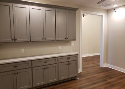 room intended for assisted living activities with entire wall of built-in gray cabinetry for supply storage and beige walls with brown flooring and white trim