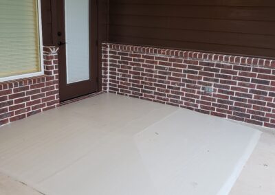 dark brown door to back porch with half dark brown siding half light red brick exterior porch walls and light gray painted concrete sloped floor