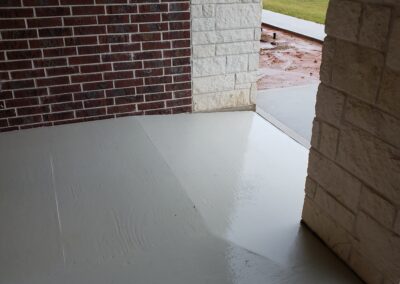 view of sloped painted concreate front porch entryway with divided red brick and white stone walls
