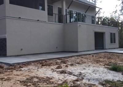 diagonal view of the back exterior of a two story tan stucco house with a second level balcony