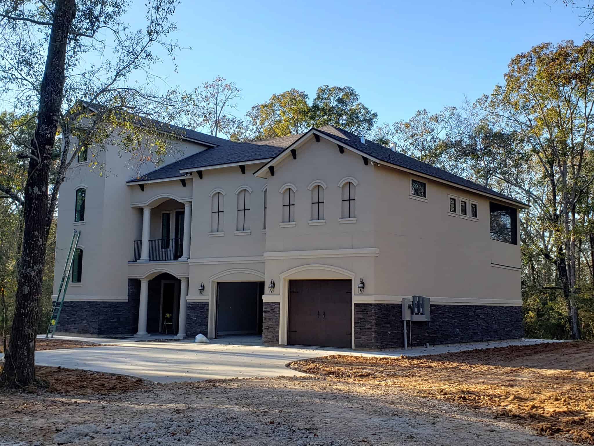 Dreams 2 Reality Custom Homes - Diaz House diagonal view of the front exterior of a two story house with a three story attached tower featuring tan stucco walls and dark brown details