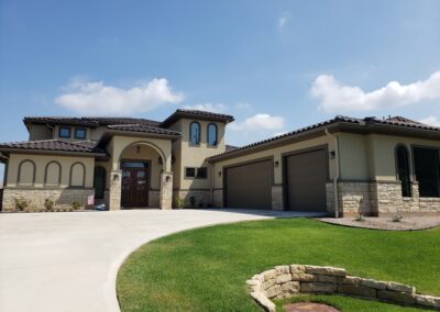 Synder custom home tan stucco and stone with dark brown accents front exterior 2 garage doors